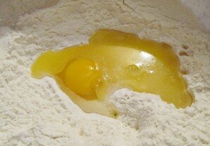 В просеянную муку разбиваем одно яйцо и добавляем 50 грамм растопленного сливочного масла, щепотку соли. 