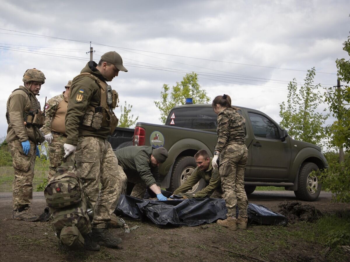    Военные медики укладывают тела убитых украинских солдат в пластиковые пакеты© AP Photo / Boghdan Kutiepov