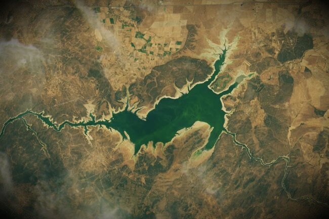 На этом спутниковом снимке НАСА показано искусственное водохранилище Вальдеканьяс, появившееся 25 июля 2019 года. Низкий уровень воды позволил древнему дольмену Гуадальпераля вновь появиться на северной стороне озера впервые за более чем 50 лет.