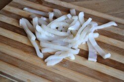 ШАГ 2:
Очищенные тубы кальмаров размораживаем, моем и нарезаем соломкой. (Можно нарезать их вначале кольцами, а потом уже после отваривания сделать из них соломку).