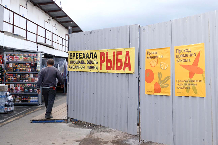    На заборе объявления: «Рынок меняется», «Московский рынок — ждите обновлений» и неожиданно подробное «Рыба переехала на площадь вдоль трамвайной линии»
