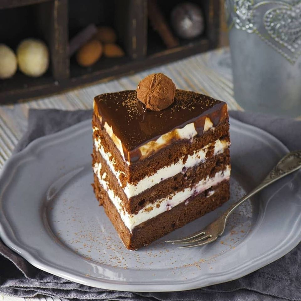 Для бисквита: 
135 грамм горького шоколада
6 яиц
135 г сливочного масла
50 грамм сахарной пудры
1/2 чайной ложки ванильного экстракта
180 г сахара
135 г муки
250 г вишневого джема

Приготовление:

Растопить шоколад на водяной бане.

Отделить желтки от белков.

Взбить масло с сахарной пудрой до гладкой, светлой, пышной массы.

Не прекращая взбивать, добавьте растопленный шоколад, ванильный экстракт, затем все желтки по одному.

Белки взбить с сахаром до жестких пиков. Добавьте белки к основной массе, аккуратно перемешивая лопаткой, стараясь, чтобы белки не сильно опали.

Просейте к смеси муку и снова перемешайте. Форму 18-20 см застелите пергаментом. Выложите тесто в форму. Выпекайте в течение 50 - 60 минут при 180 гр.

Охладите в форме, затем выложите на решётку на пол часа.

Заверните в пленку и уберите в холодильник лучше на сутки или хотя бы на ночь.
Холодный бисквит разрезать на три равных коржа.

Кремчиз:
500 г сливочного сыра
100 г сливок 33-35%
60-70 г сахарной пудры
Взбить до пиков хорошо охлаждённые сливки и сахарную пудру. Добавить сыр, взбить.
Шоколадная глазурь:

60 г жирных сливок от 33%
75 г воды
90 г сахара
35 г какао-порошка
5 г желатина

Желатин замачиваем в воде.
Воду, сливки и сахар ставим на огонь, доводим до кипения.

Всыпаем какао, постоянно помешивая доводим до кипения и снимаем с огня. Добавляем желатин и даем остыть глазури до 30 гр.

Сборка торта:
Если у вас слишком густой джем, разбавьте его 1- 3 ст л кипяченой воды. Каждый корж пропитайте вишневым джемом.

На первый корж с джемом выкладываем одну треть крема, сверху кладем второй корж, аналогично третий корж

. Убираем торт хорошо охладить, лучше на полчаса в морозилку перед покрытием глазурью.
Поливаем охлаждённый торт глазурью, оставляем в холодильнике на пару часов.