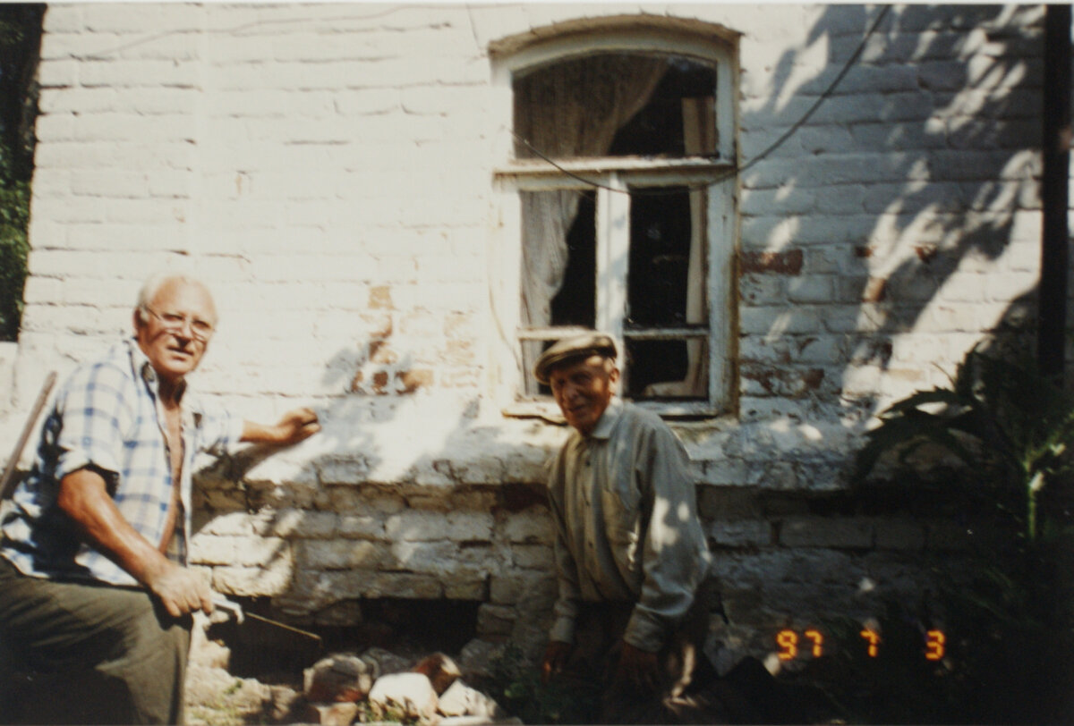 На фото – дом родной. И мы с батей. В отпуске я был. Дом маленький, но кирпичный. В 27 году отец его построил. Кирпич нам не чужой. Дед умер в 17 году. Повезло что не дожил – раскулачили семью. Имущество – что в колхоз, что поделили. Отцу и его брату отдали небольшое какое-то кирпичное строение. Сарай, что ли. Они сарай разобрали. Отец ещё кирпича подкупил – сделал этот домик. Стены засыпные – вполкирпича кладка, а в середине – известь. В том отпуске я наш дом ремонтировал и расспрашивал отца про войну.