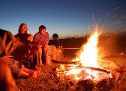 Ах, с каким нетерпением ждут тёплых дней заядлые походники, рыбаки и любители длительных путешествий. Можно взять рюкзак и удочки и отправиться куда-нибудь подальше от родной деревни, а тем более города. Но отправляясь в подобные путешествия, каждый походник должен обладать недюжинными знаниями и навыками одинокого времяпрепровождения вдали от цивилизации. В противном случае приятное уединение с удочками может обернуться трагедией, подчас непоправимой. Итак, что же должен уметь человек, отправляющийся в путешествие? Во-первых, ориентироваться на местности даже ночью, во-вторых, оказать самому себе первую медицинскую помощь. В-третьих, знать и уметь отличать съедобные грибы и растения от несъедобных. Ну, и конечно, знать способы и правила разведения костра и соблюдать их. А каковы эти правила, и поговорим сегодня. Как правильно разжечь костёр - готовим место
По правилам разведения костра первое, что нужно сделать - это подготовить место. Если на облюбованной полянке уже имеется кострище, то именно его и нужно брать за основу будущего костра, даже если оно устроено неправильно. Если же кострища нет, то место под костёр нужно подготовить с нуля. Для этого с площади радиусом в полтора метра удаляем всю сухую растительность, высокорослую траву, опавшую листву и веточки, сгребаем и сметаем любой сушняк. Далее необходимо вокруг будущего костра создать защитное минерализованное кольцо. Делается это так. От центра расчищенного места откладывается метр и рисуется круг с этим радиусом. Затем от той же центральной точки откладывается радиус в полтора метра и снова рисуется круг. В итоге перед нами два круга с расстоянием между их границами в полметра. Вот эти-то полметра и будут играть роль минерализованного кольца. С этой окружности снимаем весь верхний слой вместе с растущими на нём растениями, корешками и листовой подстилкой. На обнажённом минеральном слое почвы гореть нечему, поэтому он будет гарантированно защищать от огня окружающую природу.
Так как разжечь костёр без дров невозможно, следующим шагом будет подготовка топлива. Для розжига годятся только сухие ветки, листья и палочки, а также старый мох, растущий на соседних деревьях. Собранные дрова нужно сложить в центре кострища или в виде стога, или в виде веера. Поверх дров или под них подкладываются новые веточки и палочки по мере сгорания предыдущих. Это так называемая подкормка огня. Укладывать все дрова желательно в одном направлении, так костёр будет лучше и дольше гореть. По этому поводу у народов крайнего севера даже есть поверье, что огонь не может съесть то, что положили поперёк рта. Как развести костёр, или Махмуд, поджигай
Когда место под костёр готово, поленья и поджигающий материал сложены, наступает время разводить огонь. И на этот счёт тоже существуют определённые правила. Во-первых, зажигать костёр нужно не от удерживаемой в руке спички, а от подожженной свёрнутой в трубку бумаги или тлеющего куска мха. Во-вторых, при поджиге растопки, руки нужно держать над минерализованным кольцом, а не за его пределами. И, в-третьих, подожженную бумагу или мох следует аккуратно положить сверху на дрова или подсунуть под них, а не кидать в кучу дров, как это делают неопытные новички. И не забывайте время от времени подкармливать свой костерок и помешивать угли.
Техника безопасности при разведении костра
Ну, и в довершение всего нужно рассказать, как сделать костёр безопасным источником тепла и средством приготовления пищи, а не причиной жестокой трагедии. Для этого всего-навсего необходимо придерживаться следующих нехитрых правил:
Разводить костёр можно только на открытом месте в приличном отдалении от деревьев и кустарников, а не под кронами деревьев.
Категорически запрещается разжигать огонь в любом хвойном лесу, а также в местах лесосеки, буреломов, сильного потока воздуха, возле торфяников и в период повышенной пожароопасности.
Нельзя оставлять костёр на ночь, когда все туристы спят, и за огнём никто не следит. Он может перекинуться на соседние растения, а также в огонь могут попасть спящие возле костра люди. Нельзя засиживаться у костра допоздна, когда уже клонит в сон. Тепло расслабляет, и уставший человек может, уснув, свалиться в огонь и получить тяжёлые ожоги. Да и пожар вызвать таким образом, дело не хитрое.
Зная способы, как разжечь костёр, и соблюдая приведённые здесь правила, вы всегда будете в безопасности, а воспоминаний о совершённом путешествии хватит на всю оставшуюся жизнь.
