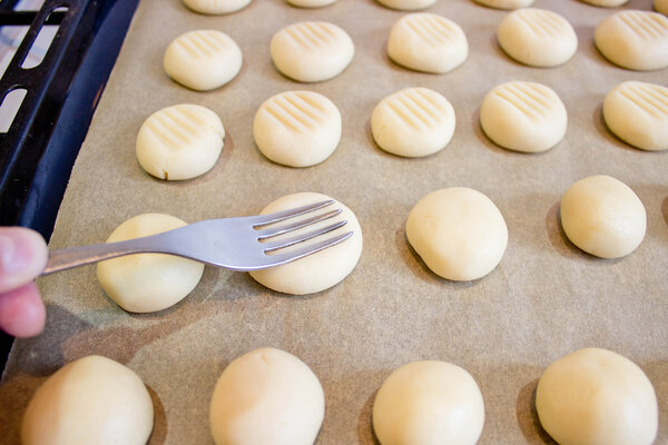 Сформированное печенье на противне, прижатое вилкой