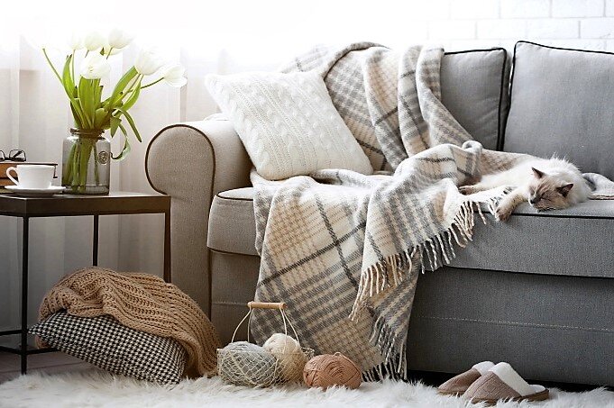 Шерстяной плед и декоративные подушки создают уют и тепло.