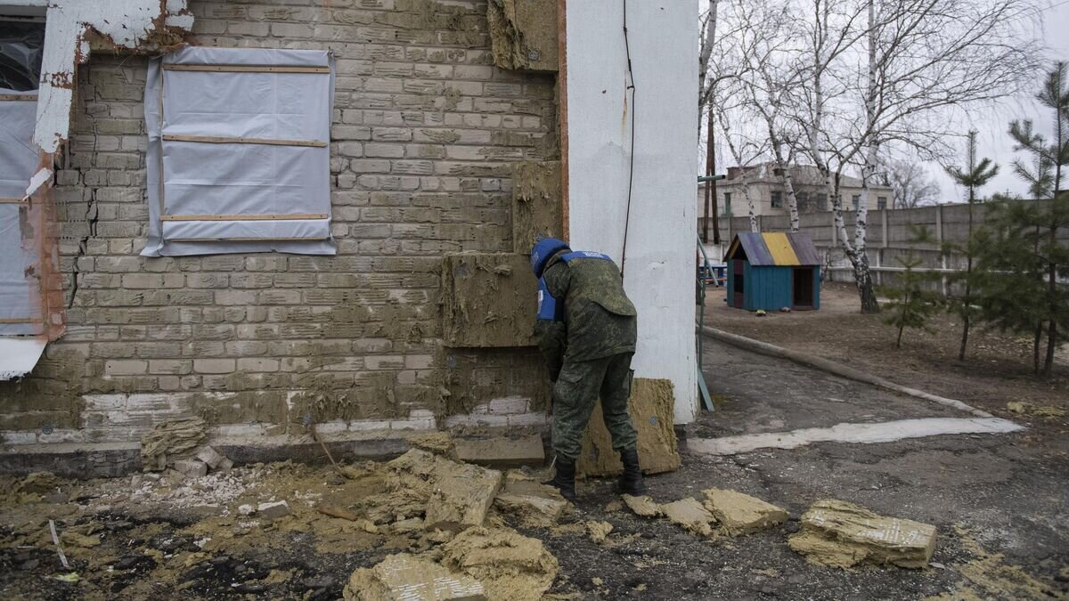    Сотрудник СЦКК у детского сада в станице Луганской, пострадавшего в результате обстрела© РИА Новости / Валерий Мельников