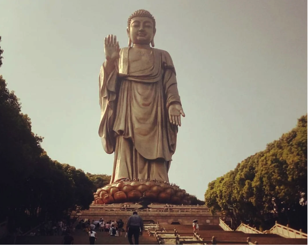 Можно увидеть крошечных людей на цветке лотоса у ног Будды.