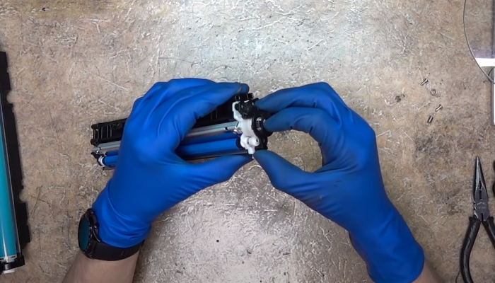 Фото 53. Вставляем кусочек плотного полиэтилена в промежуток между дозирующим лезвием и роликом подачи тонера