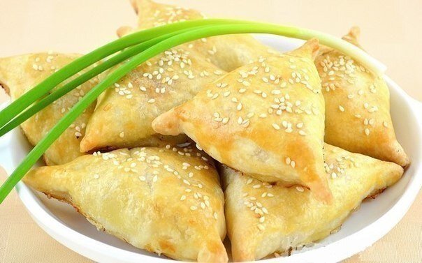 Ингредиенты: 250 г муки
100 г масла
700 г курицы (2 окорочка)
200 г лука
желток для смазки
кунжут для посыпки (по желанию)
соль
перец
Самса – очень популярное блюдо среднеазиатской кухни. Часто готовится из баранины c добавлением курдючного жира, а также из курицы, тыквы, зелени. Тесто для самсы в основном используется слоеное. Чтобы сделать такое тесто – обычно сначала вымешивают муку с водой, потом раскатывают получившееся тесто в очень тонкий прозрачный пласт на всю ширину стола, смазывают маслом или жиром, аккуратно заворачивают в рулет. В общем, занятие не из простых.
Я решила попробовать сделать слоеное тесто для самсы упрощенным способом, и не прогадала, - самса получилась великолепная – тонкое хрустящее слоеное тесто и нежная куриная ароматная начинка. Получается 14 штук.

Приготовление:
Готовим тесто.
В емкость положить муку и 1/3 ч.л. соли.
Туда же натереть на крупной терке масло (из холодильника).
Периодически перемешивать его с мукой, чтобы кусочки не слипались.

Хорошо перемешать, влить 100 мл холодной воды.
Руками слепить тесто в комок (долго не месить).
Поставить в холодильник на 30 минут или больше.

Готовим начинку.
Лук почистить, очень мелко порезать.

С окорочков срезать мясо, и мелко его порезать (жир не убирать, чтобы самса получилась сочнее). Из 700 г у меня получилось примерно 500 г куриного мяса.

В емкость положить лук, куриное мясо, соль (я положила 1/2 ч.л.), хорошо поперчить.
Перемешать.

Лепим самсу.
Тесто разделить пополам и одну часть вернуть в холодильник.
Из второй части скатать толстую колбаску и разрезать ее на 7 частей.

Каждый кусочек теста размять руками.
Затем раскатать в тонкий круг диаметром примерно 12 см (при необходимости подсыпать муку).

На середину выложить большую горку начинки.

Поднять два края, слепить их между собой.

Поднять третий край, слепить.

Также хорошо придавить уголки.

Перевернуть, получается остроконечный треугольник.
Затем тоже самое повторить для всего остального теста.

Полученные заготовки выложить на противень, застеленный пекарской бумагой.
К желтку добавить ложку воды, взболтать. Смазать заготовки.

Сверху по желанию немного посыпать кунжутом.
Поставить в разогретую до 180 градусов духовку. Выпекать 40-50 минут до легкой золотистой поверхности.

Самса очень вкусная в горячем виде.


