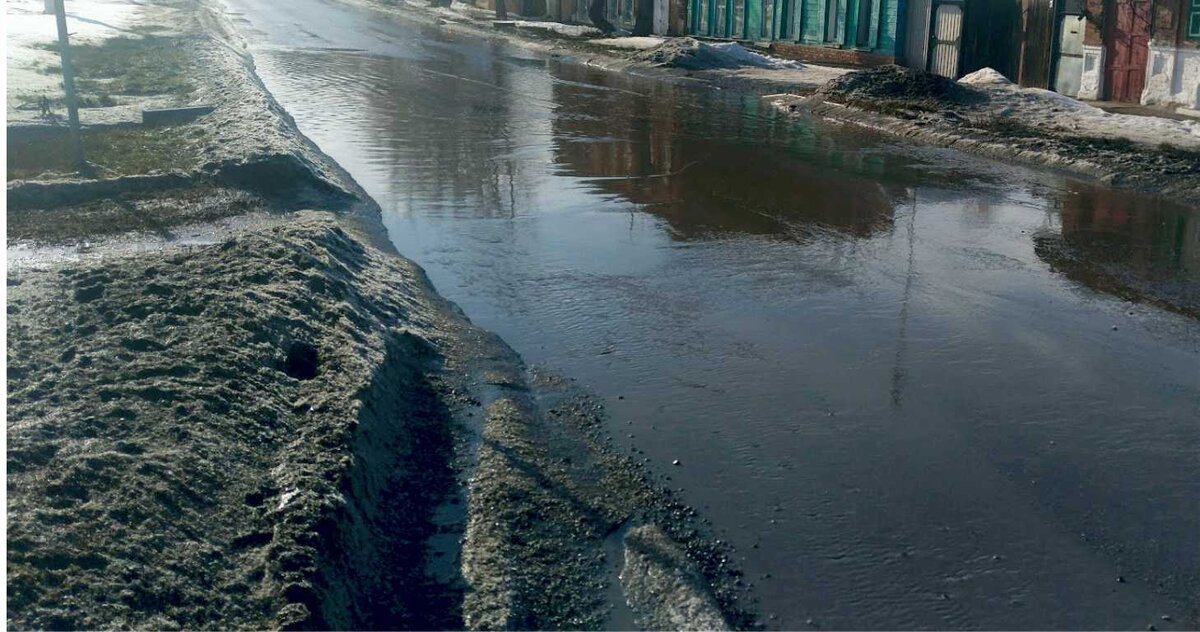 Городская дорога во время паводка. Снег на обочине превращается в лужу.