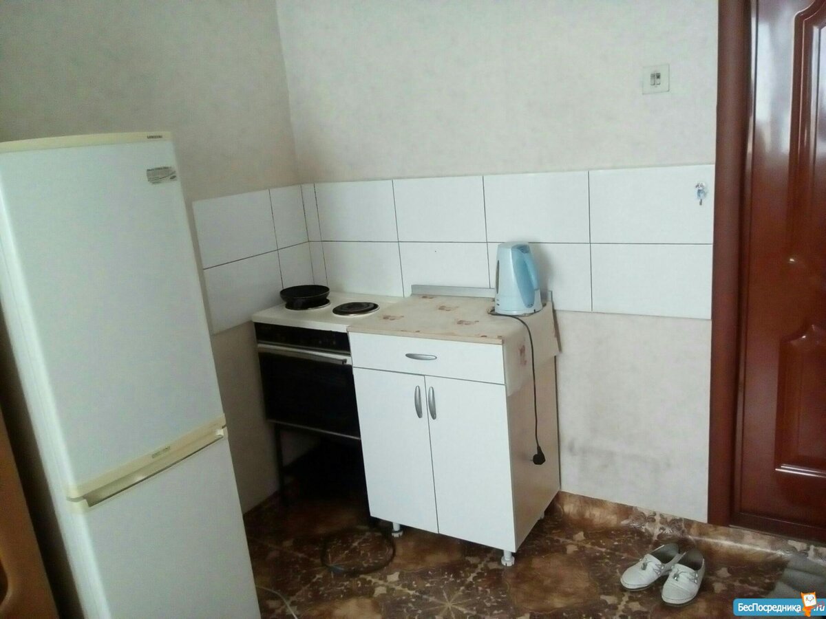 Комната не больше 16 квадратных метров, в маленькой прихожей оборудована кухонька с несколькими шкафчиками и электрической плитой. 