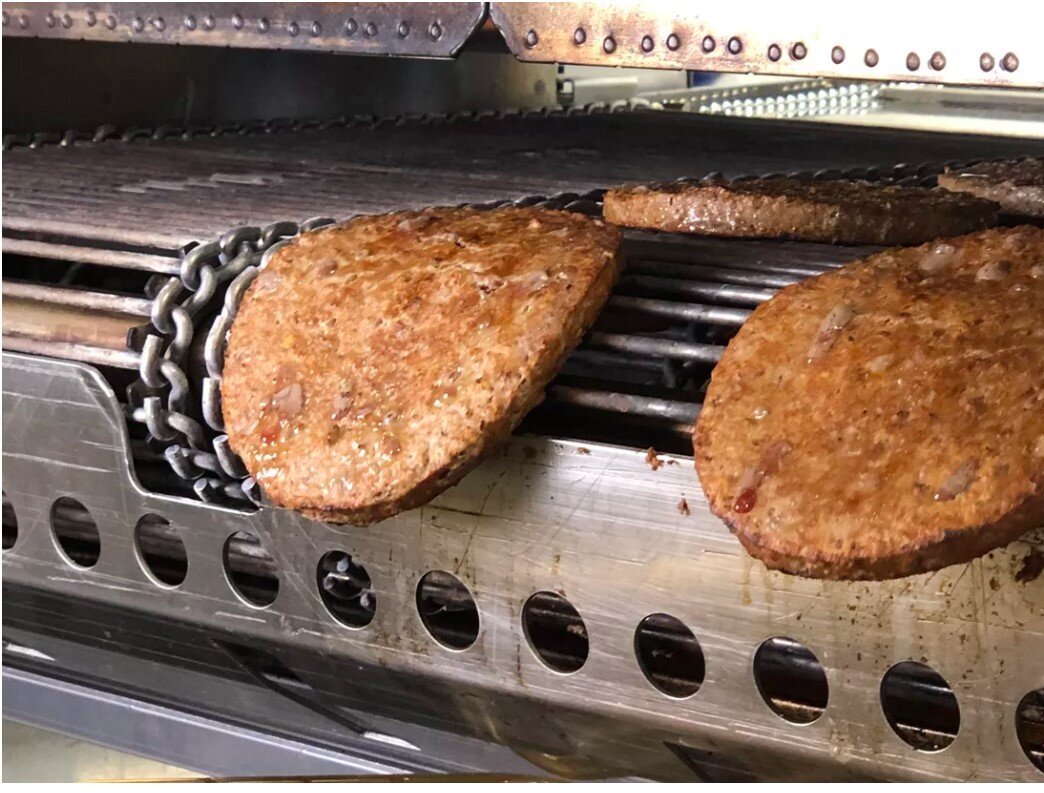 ленточный гриль на котором жарятся котлеты для бургеров в Бургер Кинг