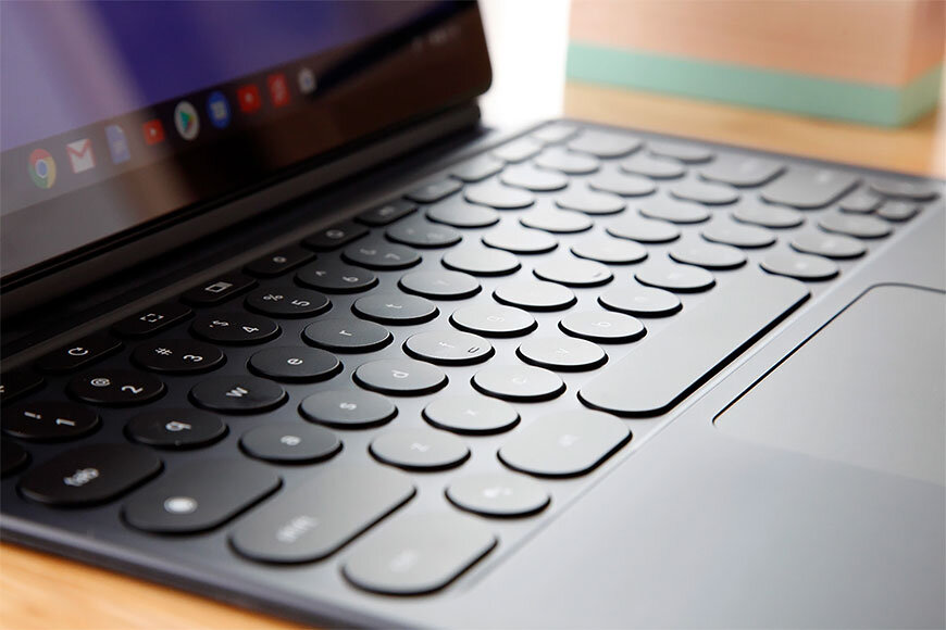 Клавиатура Google Pixel Slate выглядит как чехол у Surface Pro. Она складывается также как клавиатура iPad Smart Keyboard, но имеет оригинальный поворот. Верхний изгиб магнитами крепится к задней части устройства, что позволяет плавно изменять угол наклона одной рукой. Эта клавиатура предлагает отличный опыт набора текста. Несмотря на круглые клавиши текст набирается быстро и удобно, к тому же она очень тихая. Есть подсветка клавиш, но она либо включена, либо выключена, без всяких эффектов.