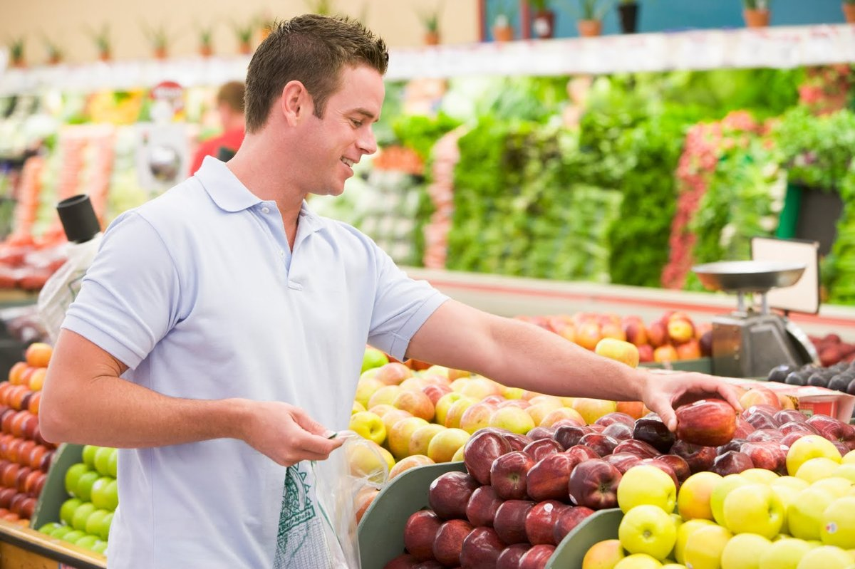 Buying fruits. Человек с продуктами. Парень в магазине продуктов. Люди на рынке. Мужчина выбирает продукты.