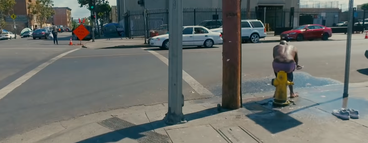 Человек принимает душ прямо на улице