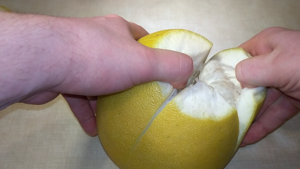 Разрезаем помело на 4 части и снимаем кожуру