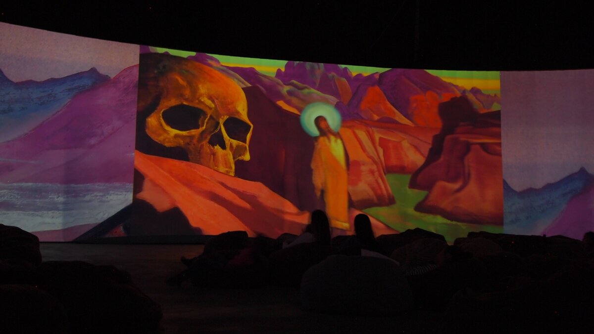 Картины Николая Рериха на заднем фоне, а на переднем мы видим торчащие головы вольяжной парочки