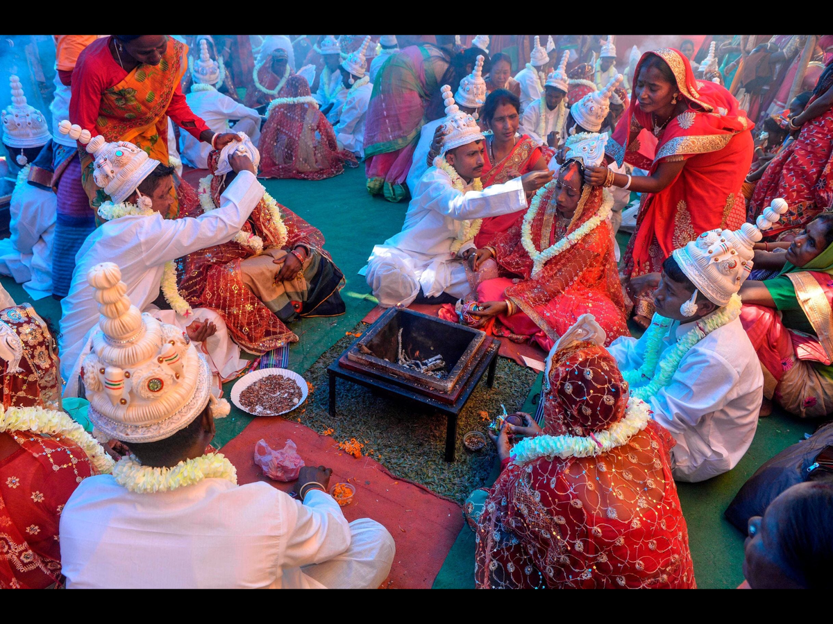 Невестки и женихи из племени «Адиваси» принимают участие в массовой церемонии бракосочетания во время религиозной конференции в чайном саду «Муни близ Багдогры», Индия. Фотограф Diptendo Dutta.