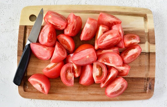 Помидоры вымойте и обсушите. Вырежьте острым ножом основания плодоножек. Плоды нарежьте крупными дольками (каждый помидор — примерно на 8 частей).