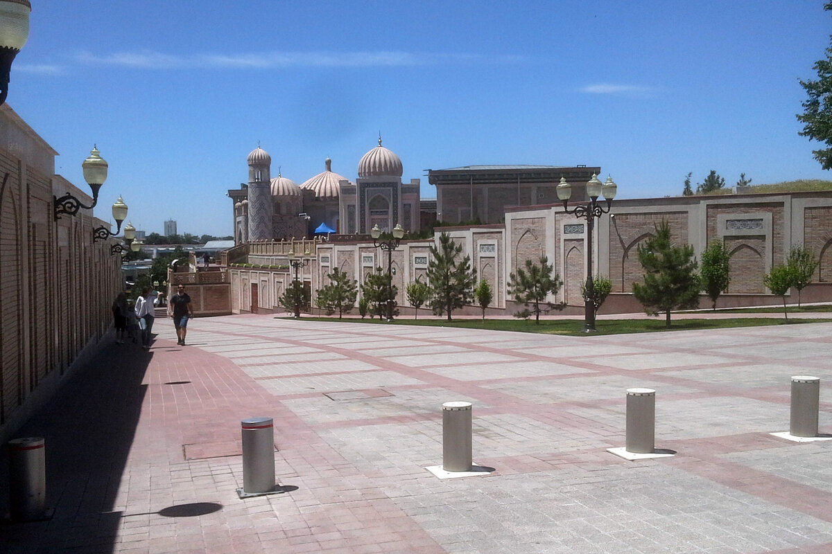 Улица Ислама Каримова вымощена ровной современной плиточкой. Слева - стена бухарско-еврейского кладбища, переходящего в кладбище Шахи-Зинда.