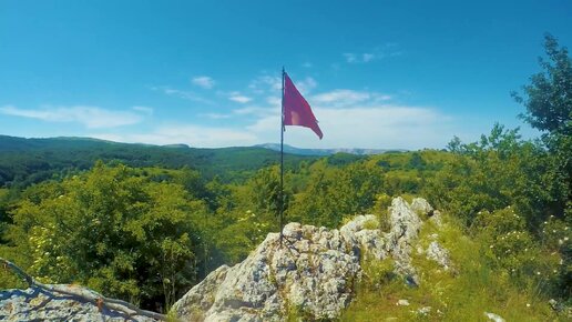 Красный флаг развевается над памятником партизанам на плато Долгоруковская яйла в Крыму