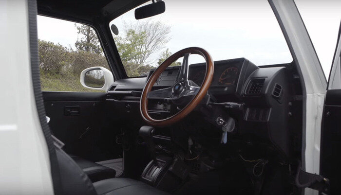 Mercedes-AMG G63 6x6 – автомобиль роскошный, сверхпроходимый, эксклюзивный и очень дорогой. Обладать им по карману немногим: все выпущенные экземпляры распроданы, а на вторичном рынке за них будут просить не меньше, чем за новые, то есть сотни тысяч евро. Однако путь для осуществления мечты за гуманные деньги есть!Правда, это будет не совсем «Гелендеваген» (точнее, совсем не «Гелендеваген»). Любопытно, что проект родился не в славящемся плагиатом Китае, а в Японии. Студенты школы автомобильных технологий NATS потратили на него всего лишь 9000 долларов, а результат оказался даже по-своему симпатичным.Взяв два внедорожника Suzuki Jimny, будущие инженеры оставили один нетронутым и приварили к нему часть кузова второго «донора». Кузов и грузовую платформу спроектировали с нуля, салон дорабатывать не стали, а фары, фонари, бамперы, решетку радиатора и фирменные эмблемы купили у дилера Mercedes-Benz. Стандартная трансмиссия 4х4 изменений не претерпела: третий мост не является ведущим, хотя и оснащен тормозами.Если по части проходимости легкая самоделка, возможно, и не уступит оригиналу с приводом на все шесть колес и тремя блокировками дифференциалов, то по динамическим характеристикам их лучше даже не сравнивать. Студенты оставили машине стандартный двигатель Jimny – трехцилиндровый турбомотор объемом всего 657 «кубиков» и отдачей порядка 60 л.с. Mercedes-AMG G63 6x6, напомним, везут 544 «лошади». Вдобавок на «японце» трудится древний и не слишком расторопный 4-ступенчатый автомат.Над проектом работала команда из 15 человек. Не исключено, что автомобильчик покажут будущей осенью на моторшоу в Токио.