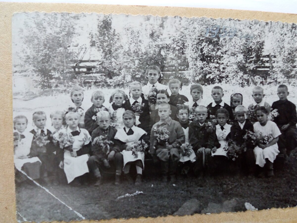 Это наш первый класс Усть-Тулатинской восьмилетней школы, Чарышского района Алтайского края. В центре моя мама, Иунихина Пана Григорьевна. Я училась у неё 4 года, до 5-го класса. Не знаю точно, все ли мои одноклассники сегодня живы. Пока вижу по фото, что восемь человек точно живы. Кое кто уехал из села еще из начальной школы. До четвертого класса состав немного менялся. Но нас было  в первом классе много. Сегодня в первый класс приходит всего 2-3 человека.