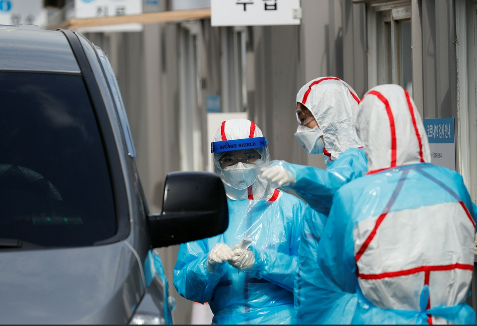 Медицинский работник готовится взять пробы у посетителя в центре сквозного тестирования в медицинском центре университета Йунгнам.