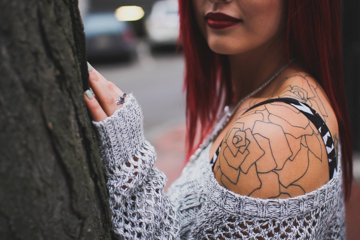 Женщина с рыжими волосами и татуировкой на спине
