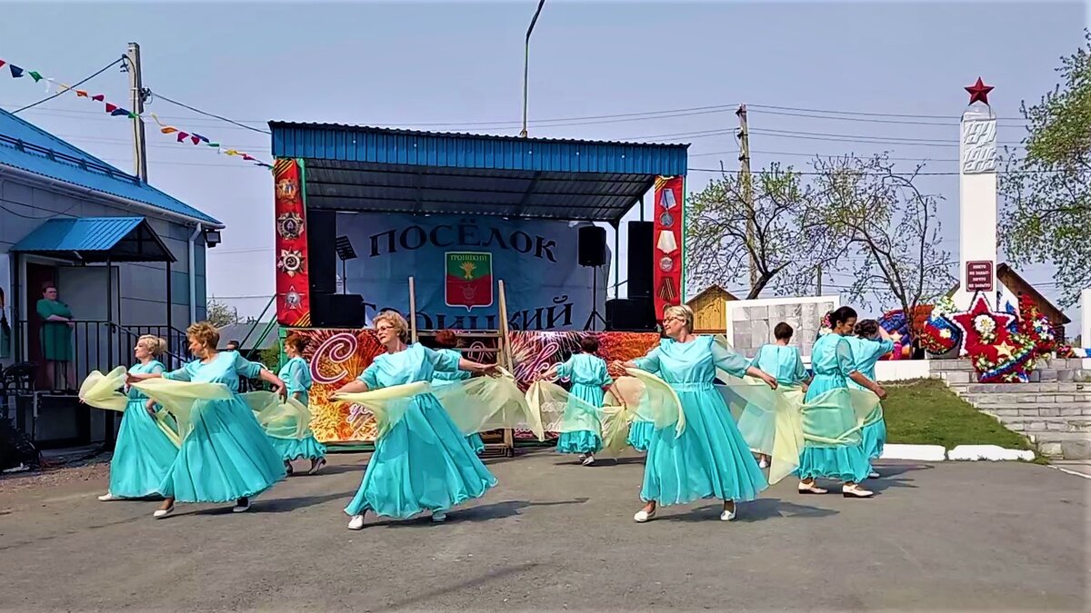 Две девушки и парень танцуют возле здания на улице