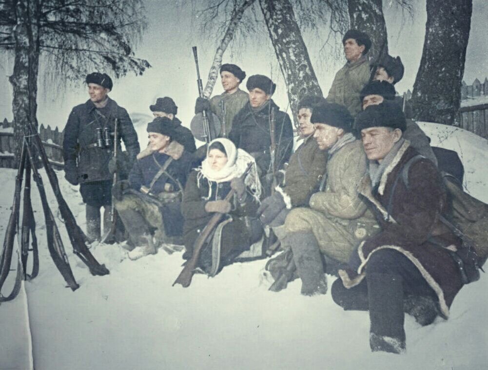 Соколовская группа партизанского отряда из 12 человек. Мужчины и одна женщина расположились в два ряда зимой на снегу. Партизанка Иванова в зимней, темной одежде, на голове повязана светлая шаль. Мужчины в полушубках и в стёганных телогрейках, на головах шапки-ушанки, на ногах — валенки. Слева — командир отряда Алексеев Алексей Федорович, справа — комиссар Семенов Петр Алексеевич. Мужчина во втором ряду держит пехотный пулемет. Слева кверху стволами стоят четыре винтовки. На обороте надпись (фиолетовые чернила): Фото Мих. Бачурина 1941-42 гг. Группа партизан отряда Солнечногорского района (Орфография автора). Источник: goskatalog.ru. Фотография использована в качестве иллюстрации.