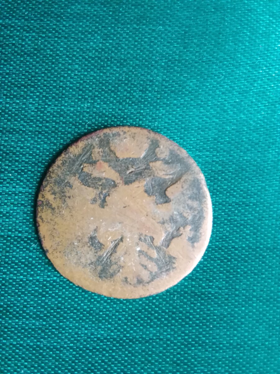  Монета "Денга" ,её оборотная сторона - реверс.  Здесь мы видим изображение двухглавого орла, увенчанного тремя коронами с царскими регалиями в лапах. Орёл с двумя головами, смотрящими в разные стороны - древнейший символ. 