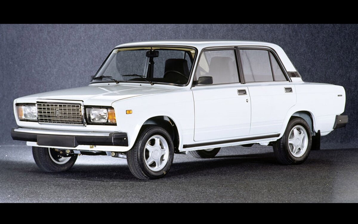 Я успел застать те времена, когда наличие у студента машины было крутым исключением, а не обязательным явлением, а вазовская «классика» считалась вполне приличным средством передвижения.


Январь 2003 года. Отнажимав онемевшими на морозе ногами педали экзаменационной «девятки», я вышел из машины на задворках Бутова абсолютно счастливым: сдал! Но до покупки первой машины мне оставалось еще больше полутора лет. Родители в «транспортном» вопросе заняли принципиальную позицию, и я, имея отменную мотивацию, стал зарабатывать на свои первые колеса самостоятельно.

Учеба на дневном отделении МГУ не оставляла много времени, но лето 2004-го сложилось для меня удачно. К осени я имел на руках 1500 долларов (около 45 000 рублей по тогдашнему курсу). О приличной Самаре, идеальном варианте для студента тех лет, пришлось забыть: денег едва хватало на живую «классику». Благо, имидж Жигулей в те годы еще не скатился к абсолютному нулю. У факультета парковались и Гелендвагены, и Subaru Impreza WRX, и BMW, однако и тольяттинская «пятерка» имела среди молодежи вес. С ней и свела меня судьба.



Изначально я приценивался к ВАЗ-2107 как к самой престижной и удобной, на мой взгляд, заднеприводной модели. Уж очень мне нравились ее высокие сиденья. И тут коллега по работе предложил купить его 21053. Шестилетняя машина пробежала 95 000 км и, по словам продавца, была «в идеале». Подкупила она приятным цветом «синяя полночь», наличием магнитолы и «мягким» салоном (в те годы модели нередко доставался кожзам). По наивности купил не глядя, без диагностики и даже вдумчивого осмотра. Хотя чего я там мог насмотреть, имея нулевой опыт и знания? А последний ВАЗ исчез из семьи за девять лет до этого, так что и отец был не помощник.

Я и сейчас, сменив десяток подержанных машин, верю, что в первые дни после покупки автомобиль привыкает к новому владельцу, часто показывая ему свой норов. Но рекорд той «пятерки» по сюрпризам до сих пор не побит! На второй день, выезжая с работы, мне еле удалось запустить двигатель. С мыслью об обязательной чистке и регулировке карбюратора я потихоньку «чихал» в сторону дома, как вдруг на одном из светофоров получил удар в зад. Виновник скрылся с места, не тормозя, а я остался с заглохшими Жигулями на перекрестке. Крыло, задняя панель, фонарь и бампер — под замену. Представьте себе масштаб катастрофы, ведь с момента покупки едва прошли сутки. Да и лишних денег на восстановление, понятное дело, не было. А на следующее утро подбитая машина и вовсе не завелась.


Ездить на собственной машине хотелось гораздо больше, чем расстраиваться, поэтому начал решать проблемы по мере важности. Гаражный гуру подшаманил карбюратор, попутно поставив бесконтактное зажигание. Отец посоветовал недорогого жестянщика, у которого — о, чудо! — нашлась ненужная (читай: бесплатная) банка краски именно моего цвета. И через несколько дней с талоном техосмотра, страховкой и номерами я гордо приехал в университет.

Конечно, никаким «идеалом» в машине и не пахло. Первым делом выяснилось, что штатным домкратом «пятерку» не поднять, хотя пороги сохраняли видимость присутствия. Пришлось заиметь в багажнике дежурную дощечку для распределения нагрузки. В лонжеронах обнаружились дыры. Двигатель, хотя и не дымил, подъедал масло и не хотел разгонять автомобиль на трассе больше 120 км/ч. Последнее угнетало больше всего на фоне друзей, у которых «семерка» и даже «шаха» с 4-ступенчатой коробкой легко и далеко уходили за этот рубеж. Наступившей зимой быстро выяснилось, что система отопления напоминала решето, и до салона доходила малая доля из положенного вазовской «классике» тепла. Выгнутая дугой крышка багажника не препятствовала проникновению воды, так что хранить что-то ценное в грузовом отсеке было нельзя.

Но какое это имеет значение на первой — своей! — машине? Тем более что были и позитивные моменты: беспроблемные коробка передач и ходовая часть, отсутствие глюков в электрике, два комплекта свежей резины на дисках, чистый и ухоженный салон. 

Мелкие ремонты, конечно, не обошли меня стороной. За нашу совместную жизнь «пятерка» потребовала новый моторчик печки, полуось, пару прокладок и резинок, а из-за заклинившей помпы пришлось прокатиться и на «галстуке». Денег на содержание хватало. Спасибо копеечным запчастям и тогдашним ценам на бензин: на 300 рублей в «классику» заливали ¾ бака. Но главное, что автомобиль стал для меня источником дохода при абсолютно свободном графике. Как нетрудно догадаться, в свободное от учебы время я «бомбил».

Заработанного извозом с лихвой хватало на студенческие тусовки, обслуживание машины и — тюнинг. Даже если бы у меня сохранилась хоть одна фотография того ВАЗа в приличном качестве, я бы все равно подобрал для публикации другую. Стыдно! Колпаки, молдинги, дефлекторы, спойлер, «мухобойка» на капоте, подлокотник, накладка на центральную консоль — какой только «цыганщины» с рынка в Южном порту не красовалось на моей «пятерке». Были даже противотуманки на «кенгурятнике». Удивляюсь, как обошелся без оплетки на руль и синих светодиодов на кузове… 

В те времена чувство прекрасного представлялось мне несколько по-другому. Видимо, наигравшись, теперь я приемлю машины исключительно в стоковом виде, испытывая к тюнингу внешнего вида и салона стойкую антипатию. 

ВАЗ-2105 пробыл у меня ровно полгода, за которые я намотал на нем 25 000 км. Вылезать из-за руля не хотелось абсолютно! Мелкие поломки не портили жизнь: кайф от обладания своими колесами затмевал все. С этим автомобилем я получил бесценный опыт зимней езды на фантастических шинах НИИШП Ралли, научился менять расходники, обрел первые знания об устройстве и ремонте. Он научил меня многому и подарил на порядок больше эмоций, чем любая последующая машина. Но расстался я с ним все же как с обычной «железкой», а не с другом. Окончательно сдавший по кузову ВАЗ перешел в руки гостей из Азии, а ему на смену пришел новый ВАЗ-2114 с нулевым пробегом. И это была уже совсем другая планета.