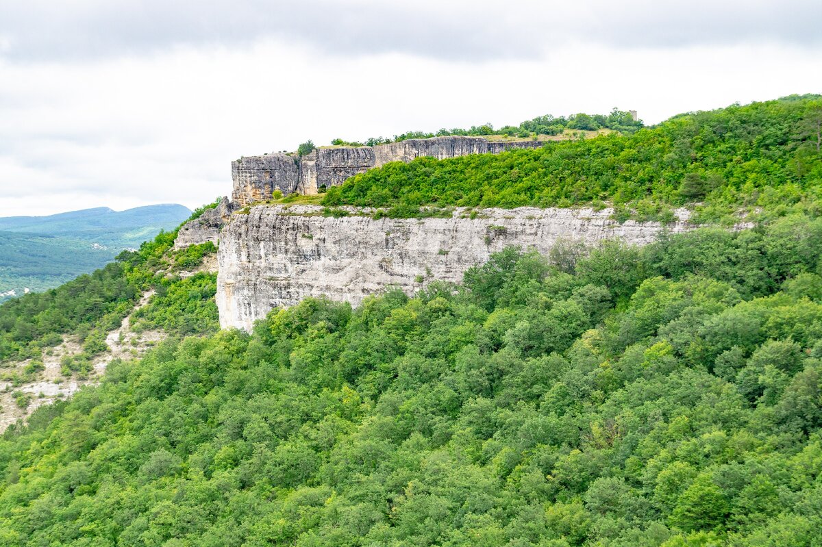 2. Два мыса пока видны друг над другом, но чуть позже расположенный ближе мыс Приятный перестанет частично заслонять мыс Башенный. Башня Сюйреньской крепости, давшая русское название мысу, видна справа, и я дошёл до этой исторической достопримечательности от места съёмки этого кадра за пять с половиной часов, так как сделал большой крюк через труднопроходимые леса на плато мыса Приятного и много раз надолго останавливался для съёмок (в том числе, и на скалах Ауз-коба). По кратчайшему пути и не останавливаясь от скал Ауз-коба до Сюйреньской крепости можно дойти примерно за час.