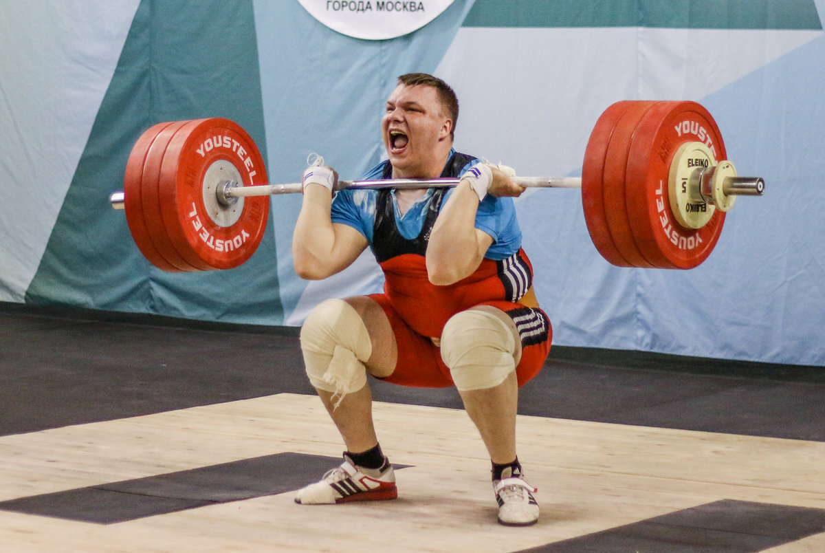 Спортсмен поднимает штангу