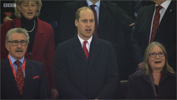 Кадр из трансляции BBC: перед началом матча герцог Кембриджский вместе с другими зрителями поет гимн валлийцев