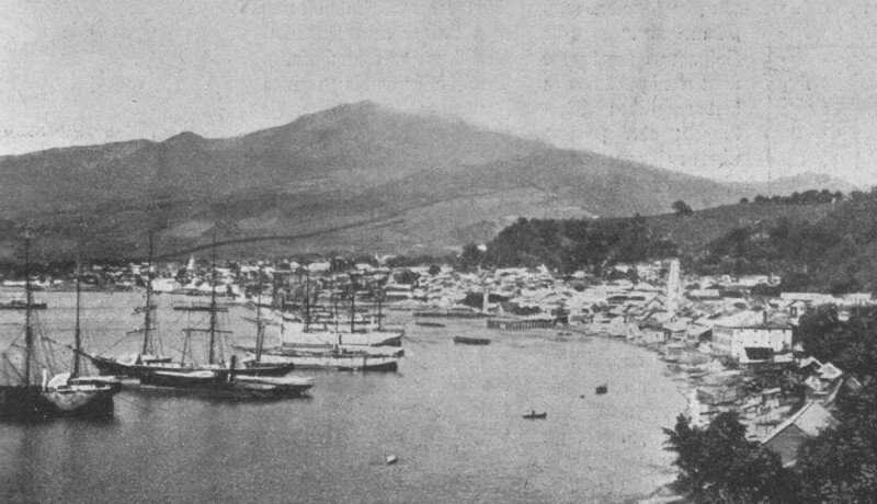 Город Сен-Пьер до извержения вулкана 8 мая 1902 года. Вулкан Монтань-Пеле на горизонте.