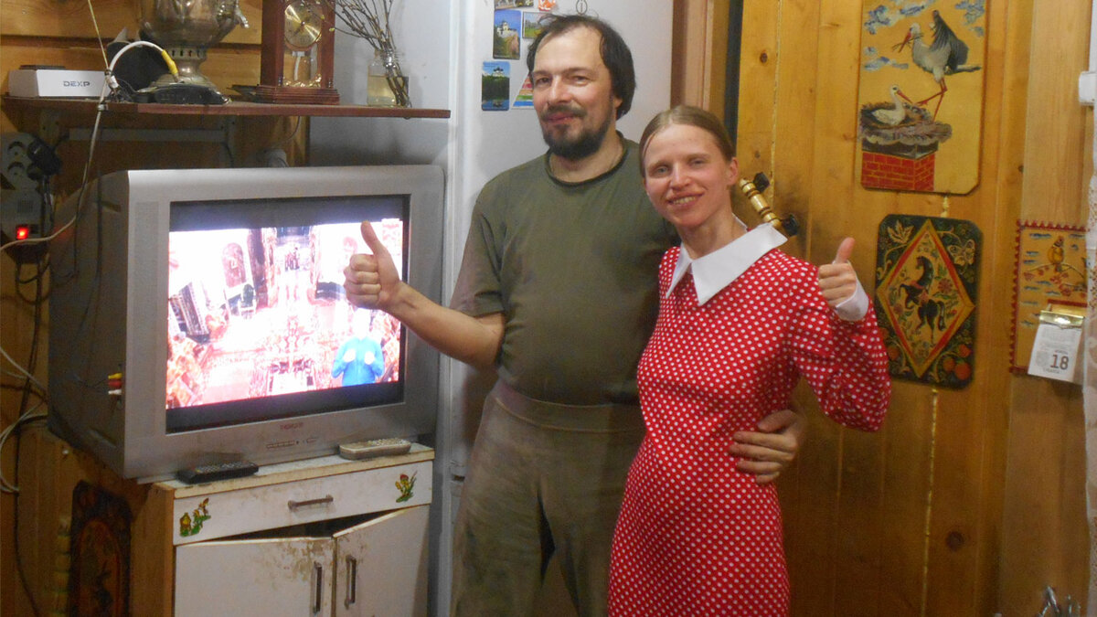 Субкультурщики в домашней атмосфере. На фото атрибуты: стиль старина и сельская местность, православная телепередача, у мужчины борода, у женщины коса и отсутствие макияжа, у мужчины однотонная одежда, у женщины длинное закрытое платье.