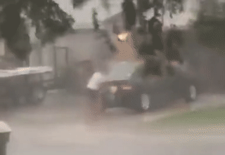 Девушка моет машину в сильный ураганный дождь.