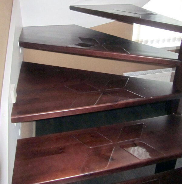 Как выглядят прозрачные накладки на темных лакированных деревянных ступенях.