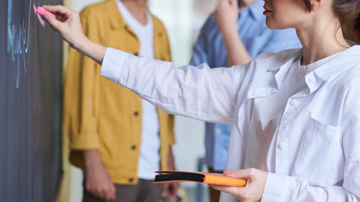    Ученица стоит у доски и пишет мелом:pexels.com