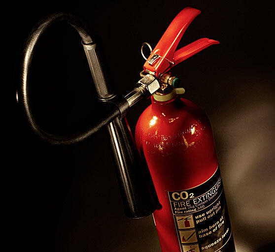 Иногда наука удивительно похожа на магию. В этом можно убедиться, научившись гасить пламя свечи газом-невидимкой.
   В список жизненно необходимых огню вещей входит топливо, тепло и окислитель — кислород. Лишите пламя любой из них, и оно быстро погаснет. Задувая свечу, мы охлаждаем ее фитиль, останавливая горение; заливая водой — еще и предотвращаем доступ кислорода. А многие огнетушители блокируют приток воздуха к горящему участку струей углекислого газа. Наблюдать, как газ справляется с пламенем, можно и дома. Для этого даже не придется устраивать пожар! На кухне наверняка найдутся и свечка, и все нужное для того, чтобы погасить ее «невидимой рукой».                                                    Нам понадобятся:
1 Свеча и зажигалка. Удобнее и безопаснее использовать небольшую свечку в форме таблетки.                                                                                                                                                                          2 Глубокая тарелка или стакан для свечи.                                                                                                              3 Стакан или бутылка с широким горлышком для получения в ней углекислого газа.                                       4 Столовый уксус (уксусная кислота) и пищевая сода (бикарбонат натрия). 
                                                                                                                                                                                          Ставим свечу на дно тарелки или стакана и зажигаем. Во вторую емкость насыпаем чайную ложку соды и наливаем около 150 мл уксуса, медленно перемешивая. Начинается реакция: уксусная кислота отнимает у соды атом натрия, и свободный бикарбонат распадается на воду и углекислый газ, который поднимается белой пеной. Это взаимодействие проходит достаточно бурно, с выделением тепла, так что будьте осторожны: емкость может нагреться. Детям следует проводить этот опыт только вместе со взрослыми.                                                                                                                                       Углекислый газ тяжелее воздуха: в нормальных условиях его плотность примерно в полтора раза выше и составляет 1,98 кг/м3. По мере протекания реакции газ наполнит емкость, и уже через полминуты его можно будет аккуратно слить в тарелку или стакан с горящей свечой. Зрелище получится более эффектным, если сначала перелить газ в пустой промежуточный стакан, а затем уже на пламя. Все будет выглядеть так, словно мы погасили огонь ничем.                                                                                   Попадая в сосуд со свечой, углекислый газ скапливается на дне, вытесняя кислород. Без него пламя быстро слабеет и гаснет. По такому же принципу работают и широко распространенные углекислотные огнетушители, которые можно найти почти в любом магазине, офисе или автомобиле. Правда, газ в них закачан уже готовый, в большом количестве и под большим давлением, чтобы, вырвавшись наружу, он мог мгновенно сбить пламя.                                                                                                                                                     Газ и электричество
Углекислый газ ток не проводит, позволяя тушить даже оборудование под напряжением. Однако расширение газа идет с поглощением тепла. Температура у сопла огнетушителя падает до −70 °C, и на нем конденсируется вода. В ней углекислый газ образует ионы угольной кислоты, и вода становится проводящей. Особенно легко это происходит на металлическом раструбе, и применять такие огнетушители для тушения техники под напряжением не стоит.