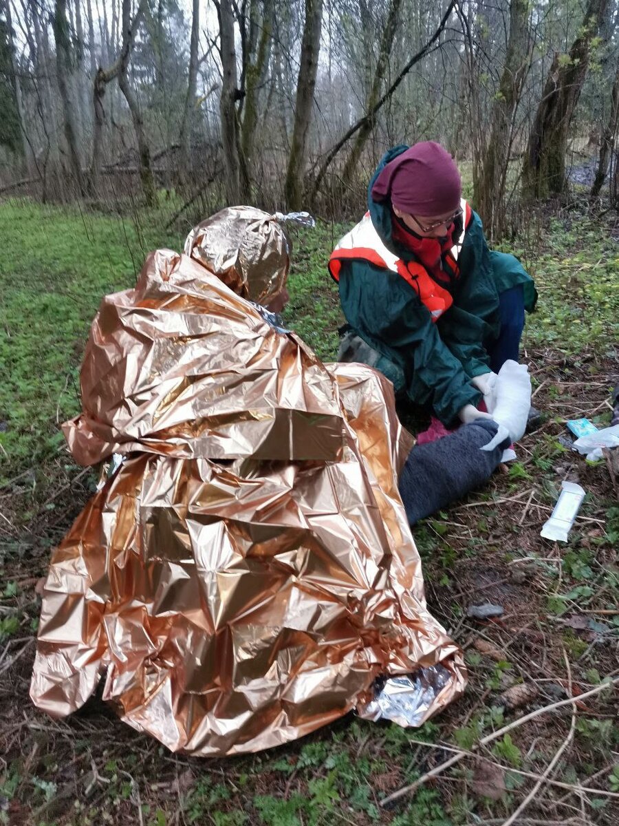 Спасатель сооружает сухие носочки для найденного в мокром лесу человека