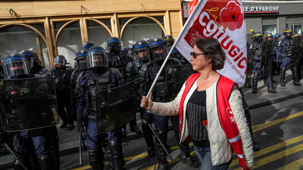 Фото: Michel Euler / AP📷Протестующая с флагом идет мимо полицейских