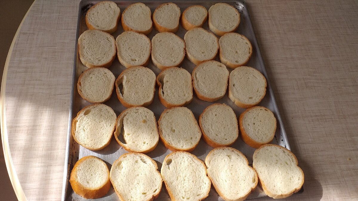 Нарезной батон разложить на лист и запекать с двух сторон по 5 минут.