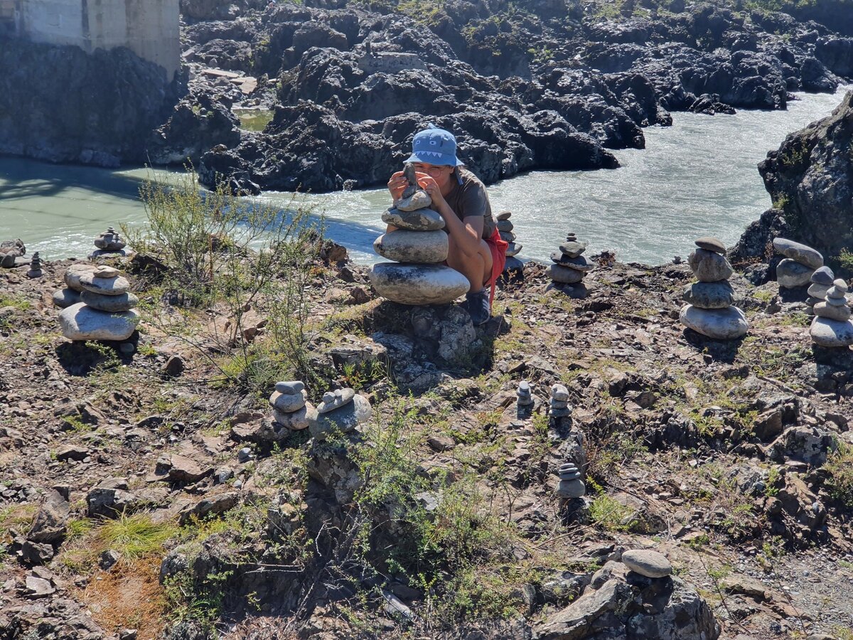 Моя целеустремленная дочь  сосредоточенно собирает пирамидку из камней . Путешествие на Алтай . Личное фото автора 