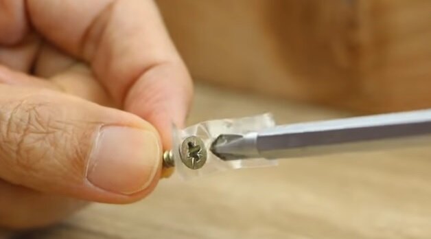 Чтобы шуруп было проще вкрутить, зафиксируем его кусочком скотча