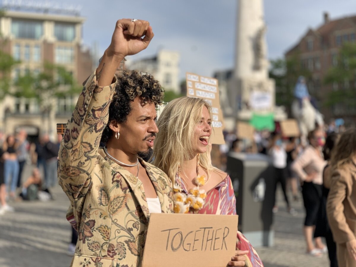  Протестующие держали плакаты с сообщениями о единстве и поддержке черного сообщества. 