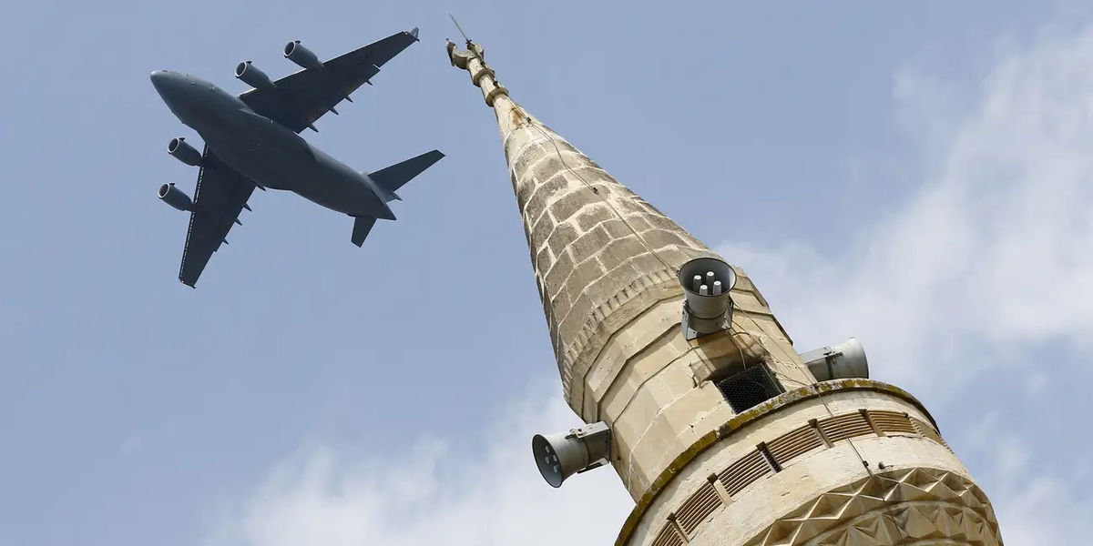 Большой транспортный самолет ВВС США Boeing C-17A Globemaster III пролетает над минаретом после взлета с авиабазы Инджирлик в Адане, Турция, фото от 12 августа 2015 года.